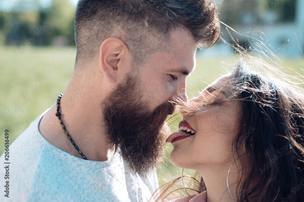 Lady with pink tongue licking bearded macho. Couple kissing outdoors