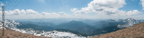 A beautiful panoramic view of the snow-capped mountains of the Carpathians from the top of Goverly in spring in a beautiful sunny day with light clouds. Carpathians, Goverla, Ukraine.