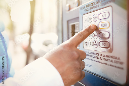 Closeup headshot of young African man trying to check balance on his credit card using automatic teller machine. Blurred background