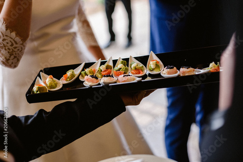 Tasty wedding appetizers served by waiters to the guests