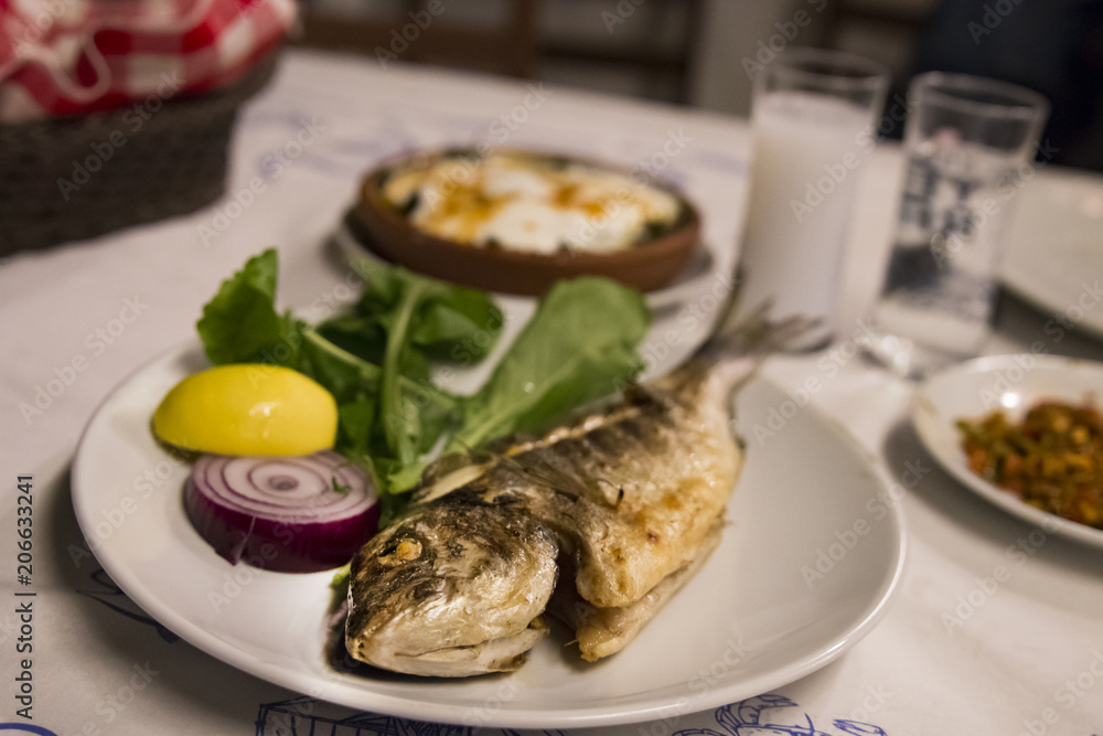 Bream fish on the plate at the dinner table with Turkish Raki. Bream fish on the plate at the dinner table with Turkish Raki.