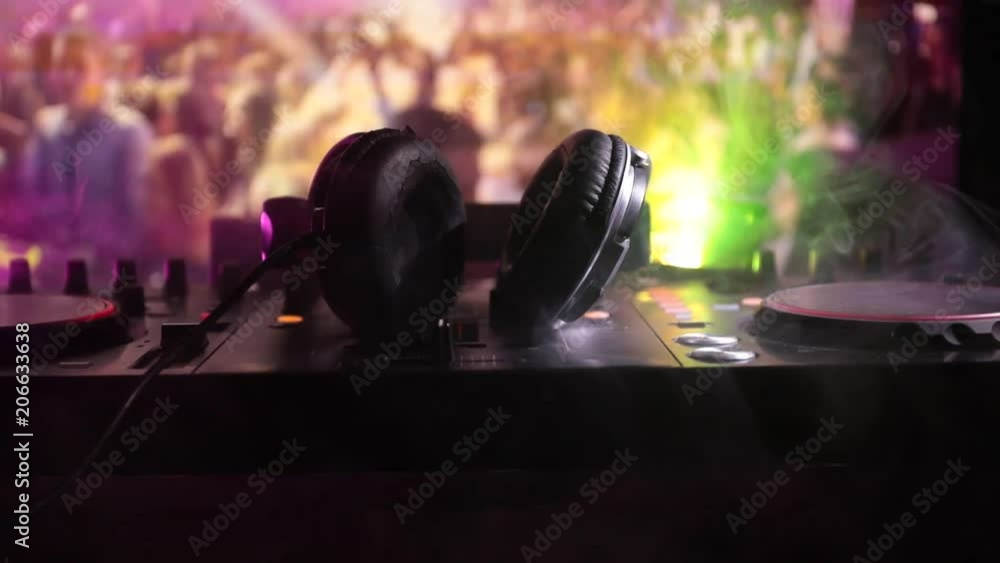 Slider shot. In selective focus of Pro dj controller.The DJ console deejay mixing desk at music party in nightclub with colored disco lights. Close up view