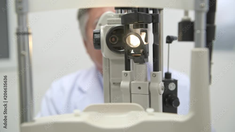 Optician at work in hospital. Senior chinese optician using eye scanner, POV style. Eye care concept. Optician at work in hospital. Senior chinese optician using eye scanner, POV style. Eye care concept.