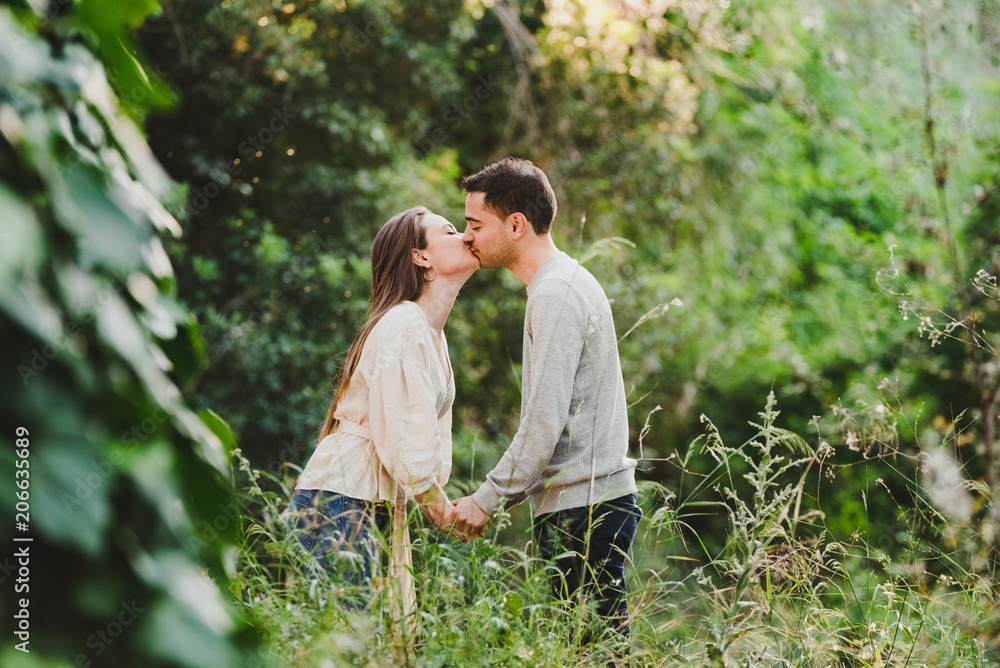 Enamored couple hugging and laughing in the middle of the green road