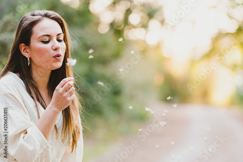 Pretty young girl blowing a flower natural