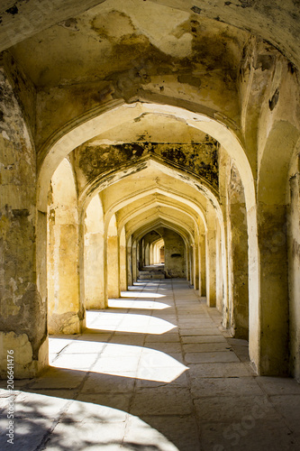 Mughal Arches Creating a Pathway along the Outside of a Tomb Appear Golden in the Sunlight at the Qutb Shahi Tombs in Hyderabad, India © E. M. Winterbourne
