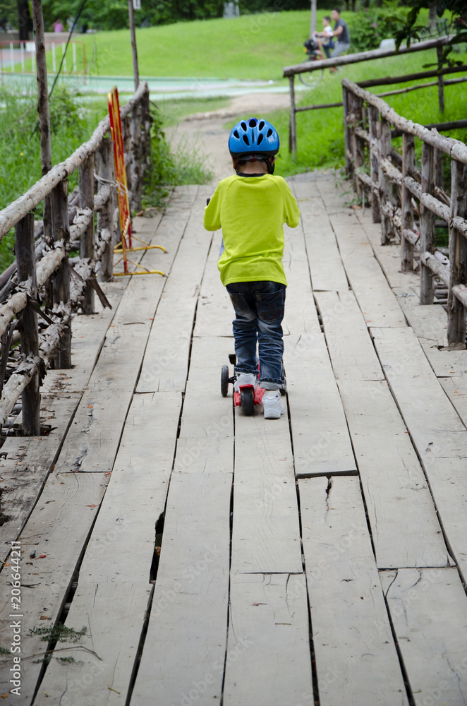 Obraz premium boy ride the scooter across the bridge