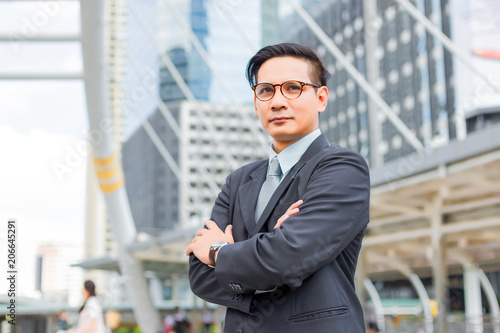 Asia young business man in front of the modern building in downtown .Concept of young business people