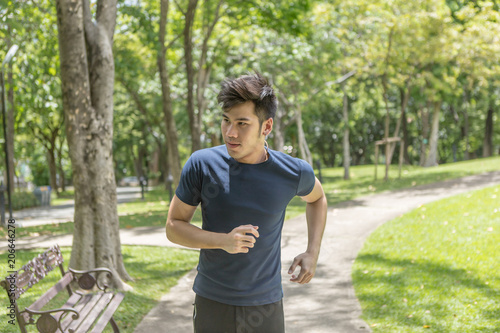 Young smiling sporty man running in park in the morning. Fitness man jogging in park.