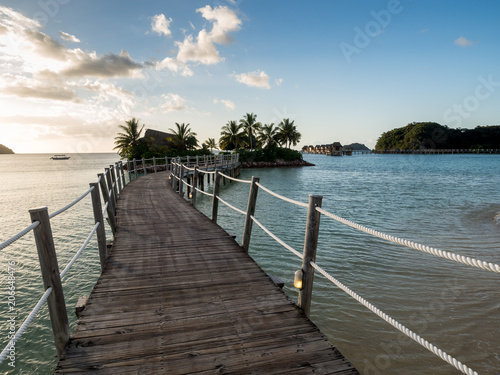 Ocean Landscape Boardwalk Walkway Over Beach out to Lone Palm Tree Island in Fiji at Sunset