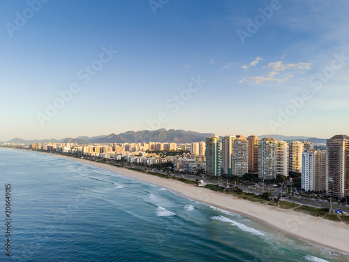aerial landscape photo of Barra da Tijuca beach , with waves crashing on beach during sunrise, with the beachfront buildings in the background © jpbarcelos