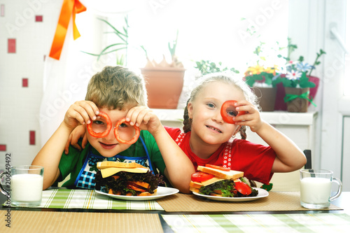 Cheerful children at Breakfast . Brother and sister with sandwiches