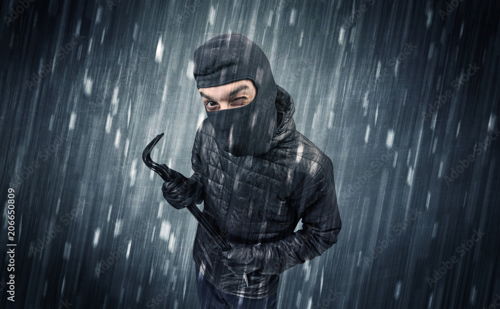 Burglar in action in black clothes with rainy concept. Burglar in action in black clothes with rainy concept.
