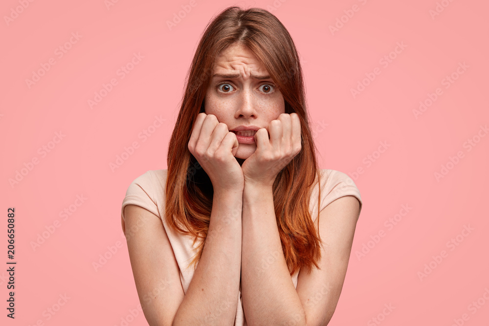 Candid shot of nervous beautiful freckled female has long dyed hair, raises eyebrows and has puzzled expression, feels frustrated after big failure, worries before something, isolated on pink wall Candid shot of nervous beautiful freckled female has long dyed hair, raises eyebrows and has puzzled expression, feels frustrated after big failure, worries before something, isolated on pink wall