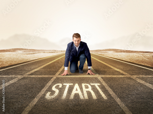 Young determined businessman kneeling before start line