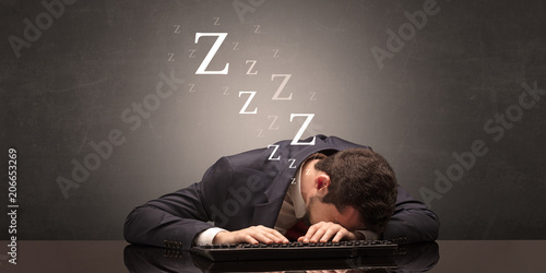 Young businessman fell asleep at the table on his keyboard concept