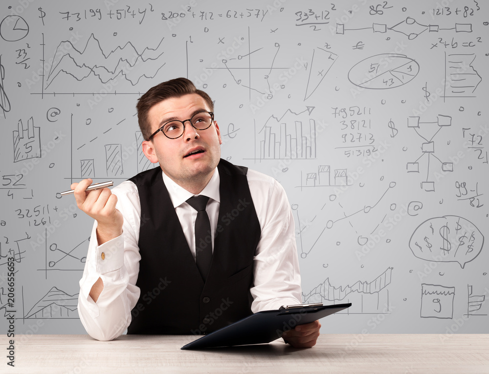 Young handsome businessman sitting at a desk with white charts behind him Young handsome businessman sitting at a desk with white charts behind him