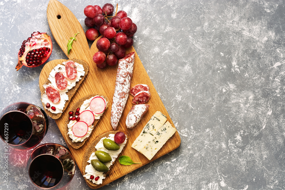 Bruschetta or authentic traditional Spanish tapas, red wine and grapes on a gray background. The view from above, flat lay.