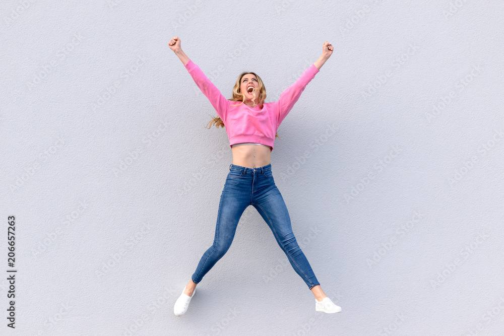Fototapeta premium Young happy woman in jeans jumping into air