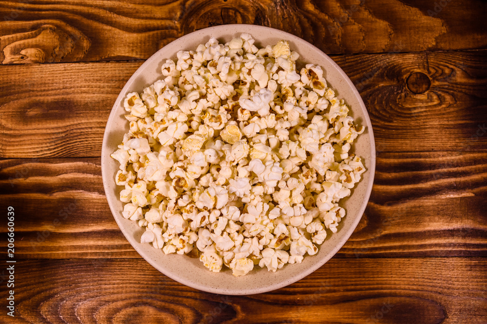 Ceramic plate with popcorn on wooden table. Top view Ceramic plate with popcorn on wooden table. Top view