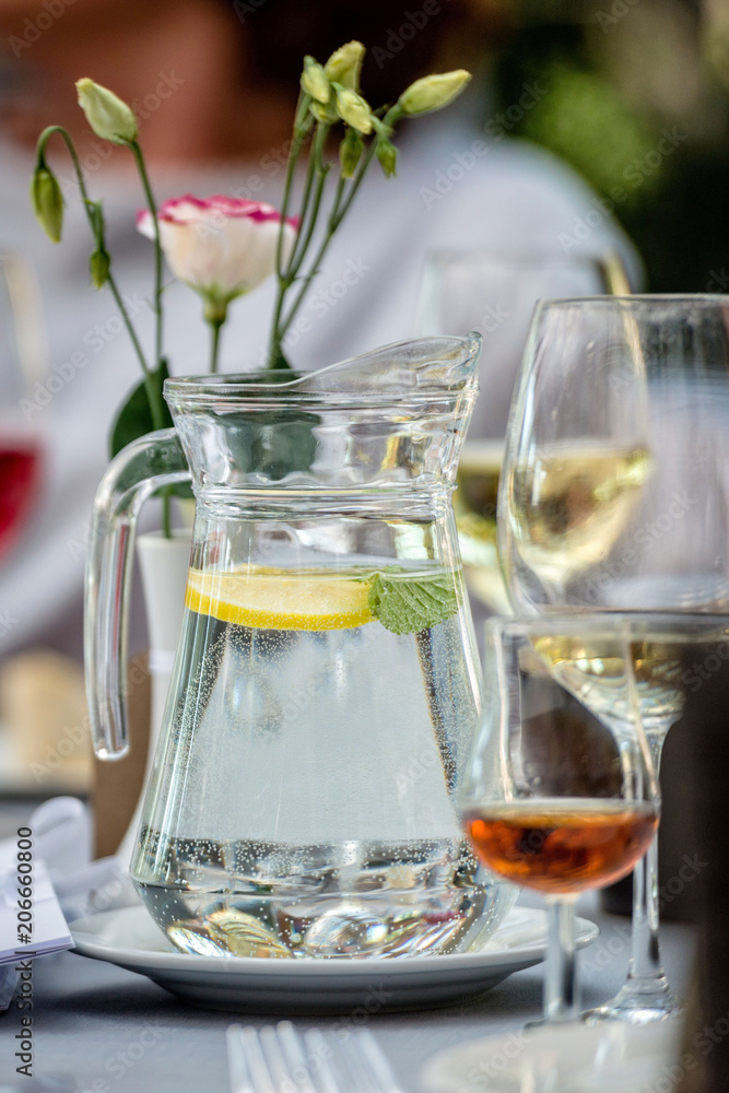 Table laying concept. On the table stands a jug with water and lemon. Glasses in the background. Table laying concept. On the table stands a jug with water and lemon. Glasses in the background.