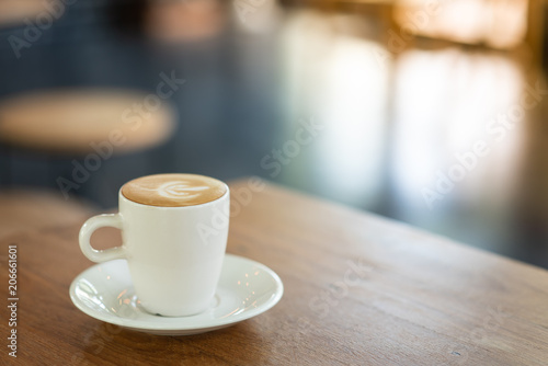 Hot Latte is placed on a wooden table in a cafe. Wait for customers to drink. To refresh the morning.