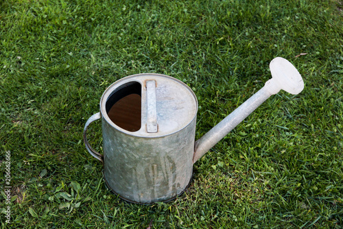 old metal watering can on the green grass