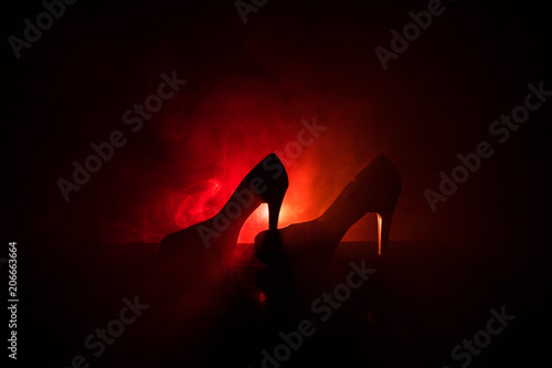 Fototapet Black suede high heel women shoes on dark toned foggy background