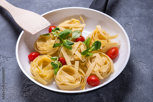 Raw Italian pasta with tomato in white ceramic pan