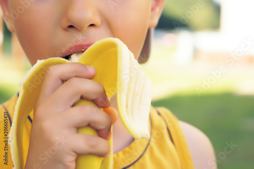 Little boy eating banana ,looking at camera with happy face, showing thumbs up. Happy kid enjoy eating fresh fruit. photo