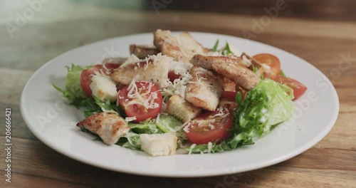 Slow motion closeup parmesan flakes falling on caesar salad photo