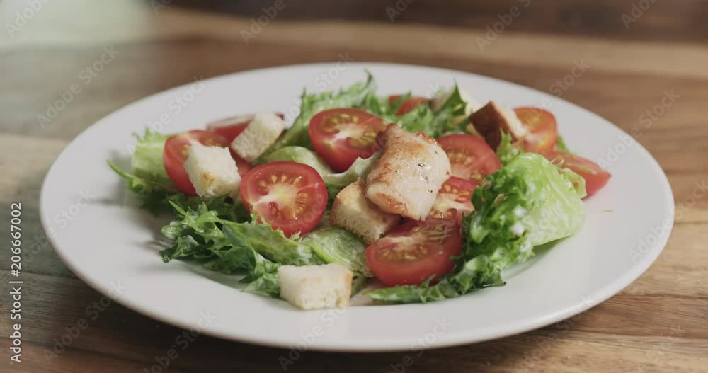 Slow motion closeup adding chicken to caesar salad Slow motion closeup adding chicken to caesar salad