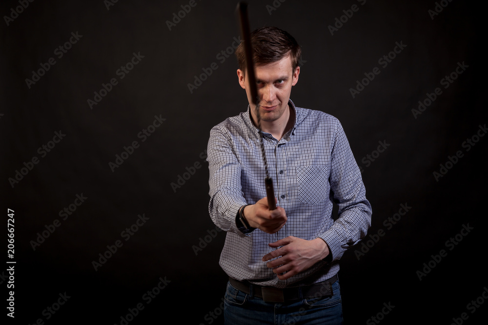 Dark-haired man in a plaid shirt holds a nunchuck in his hands .on black isolated background Dark-haired man in a plaid shirt holds a nunchuck in his hands .on black isolated background