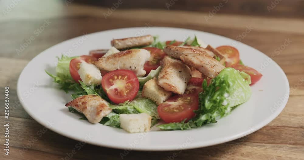 Slow motion closeup adding chicken to caesar salad Slow motion closeup adding chicken to caesar salad