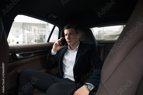Serious boss! Young smart male professional businessman seriously talking on smartphone, while going to the office by car. © stacestock