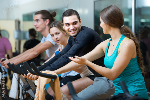 Young adults on exercise bikes in gym.