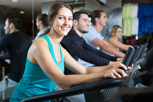 adults riding stationary bicycles in fitness club