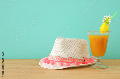 image of tropical and exotic fruit coctail next to white fedora hat over wooden table.