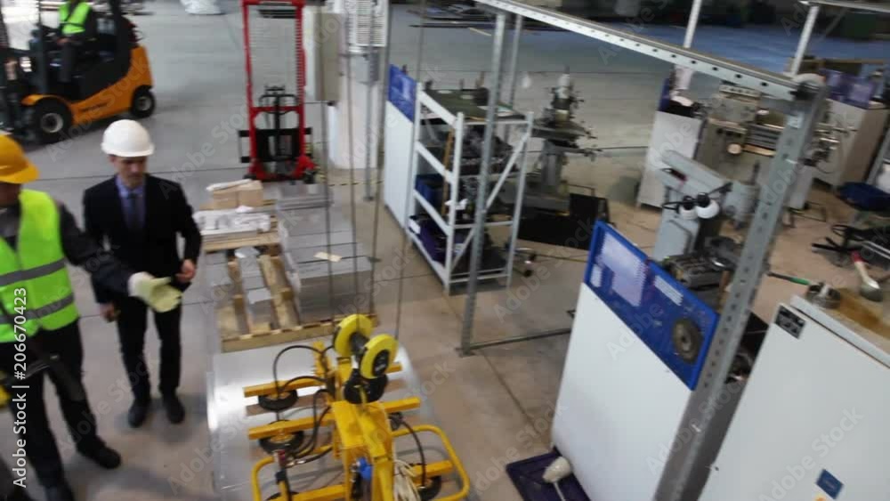 Manager and workers near metal sheet lifting device at factory Manager and workers near metal sheet lifting device at factory