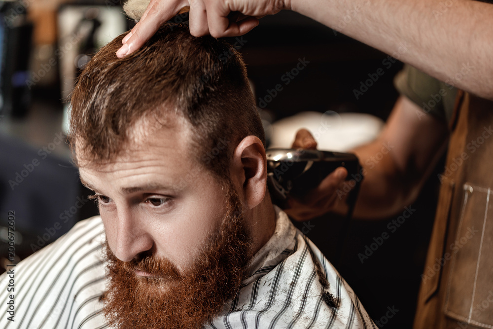 Fototapeta premium Barber and bearded man in barber shop