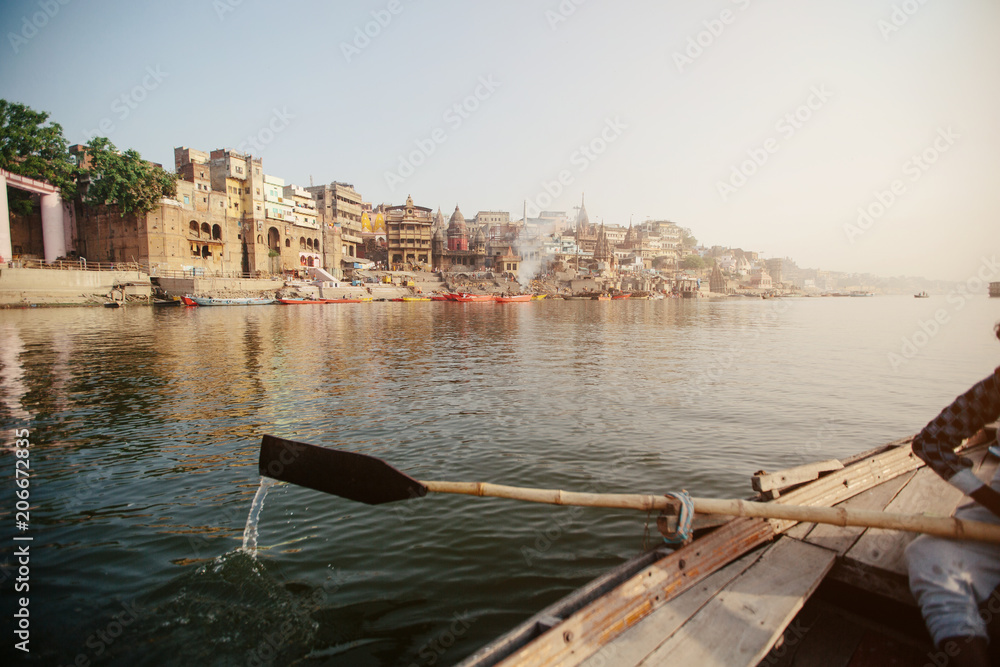Ganga river and Varanasi ghats morning view with buildings from river and boat. Smoke from bonfires