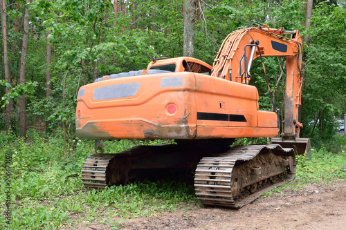 современный экскаватор строит дорогу в лесу