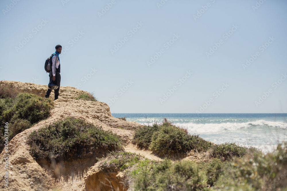 Portrait of African man standing on beautiful cliff, looking to ocean, enjoy motor travel holiday. Algarve, Portugal