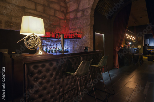 Modern jazz bar interior design, leather bar counter, lamp like music instrument design. Stone wall on background, brutal atmosphere photo