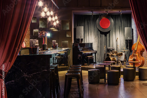 Modern jazz bar interior design  stage with black piano and cello  lamps above bar counter