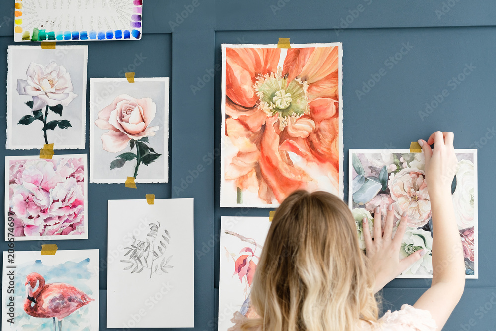 Fototapeta premium creative leisure. painting hobby. artful personality. talented girl sticking her watercolor drawings to the wall
