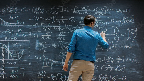 Fotografiet Brilliant Young Mathematician Is Writing on Big Blackboard and Thinking about Solving Long and Complex Equation/ Formula