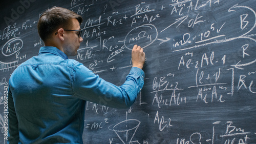 Photo Brilliant Young Mathematician Approaches Big Blackboard and Finishes writing Sophisticated Mathematical Formula/ Equation
