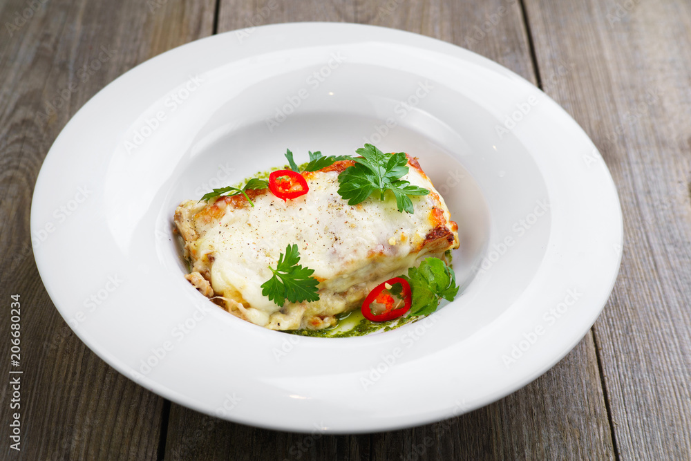 Italian national cuisine, gourmet food, banquet, restaurant menu concept. Lasagna with bechamel sauce and parsley on wooden table.
