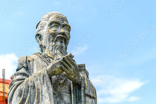 Photos closeup old statue of confucius with soft-focus and over light in the background